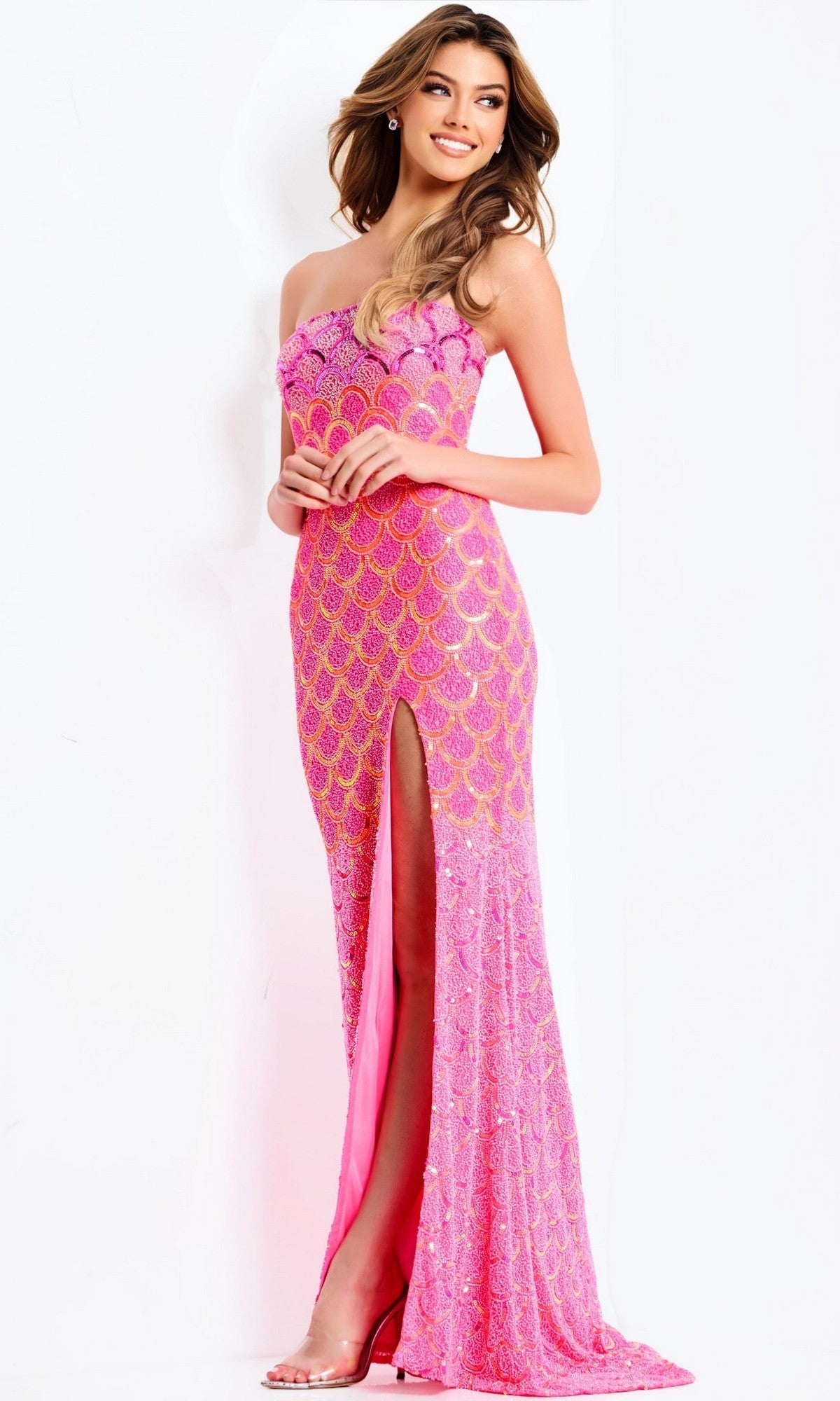 A woman poses against a white background in the Jovani 48620 long prom dress—a strapless pink gown with a thigh-high slit, gold sequin scallop pattern, and geometric beading.